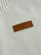 Louis Vuitton leather label on white knit fabric reading “LOUIS VUITTON PARIS”