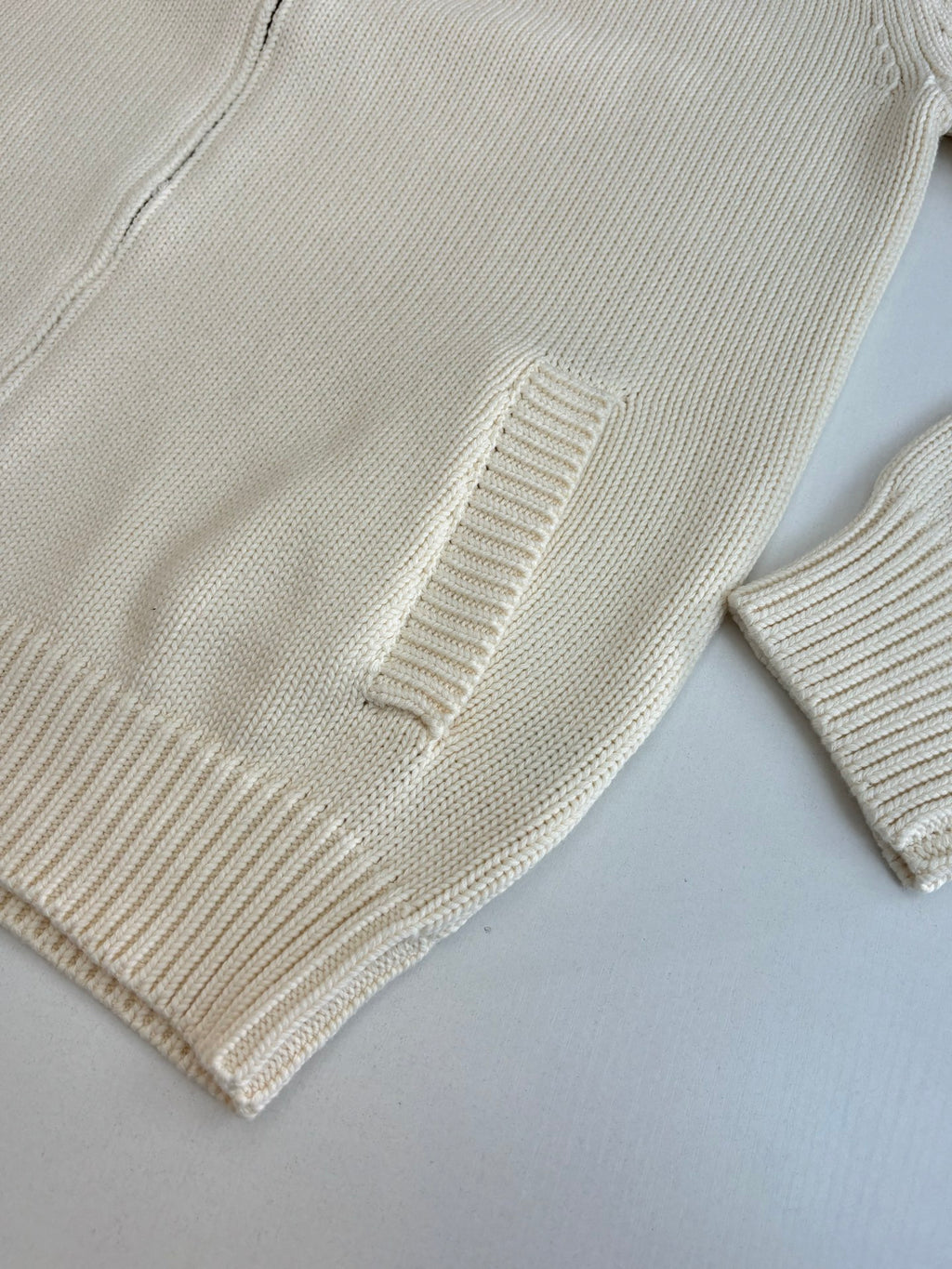 White knit sweater sleeve and hem with ribbed cuffs and textured stitch detail