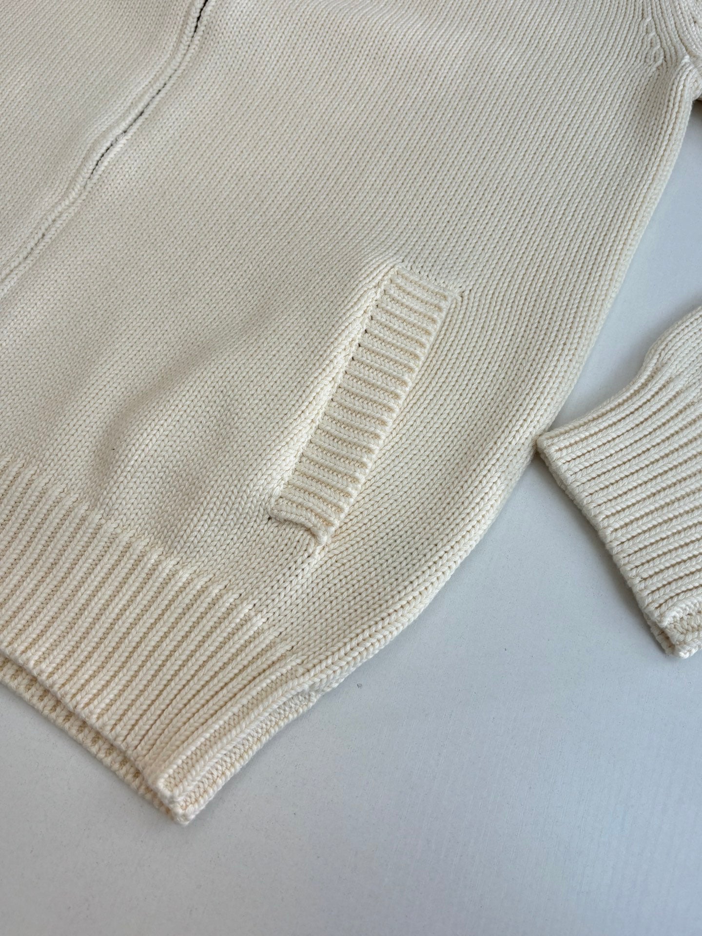 White knit sweater sleeve and hem with ribbed cuffs and textured stitch detail