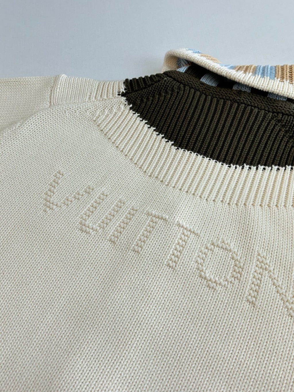 White knit sweater neckline with contrast black stripe and embossed LV logo