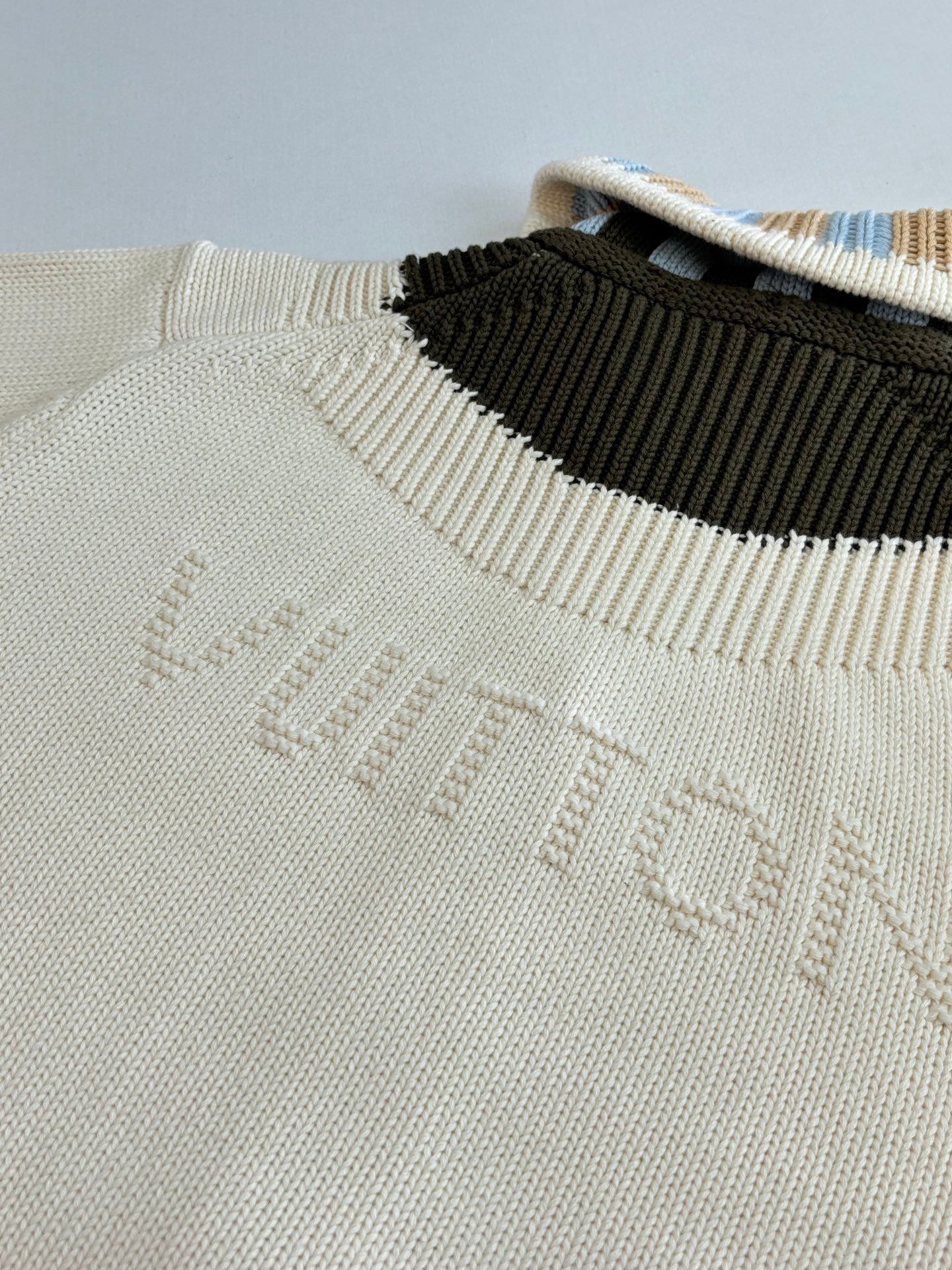 White knit sweater neckline with contrast black stripe and embossed LV logo