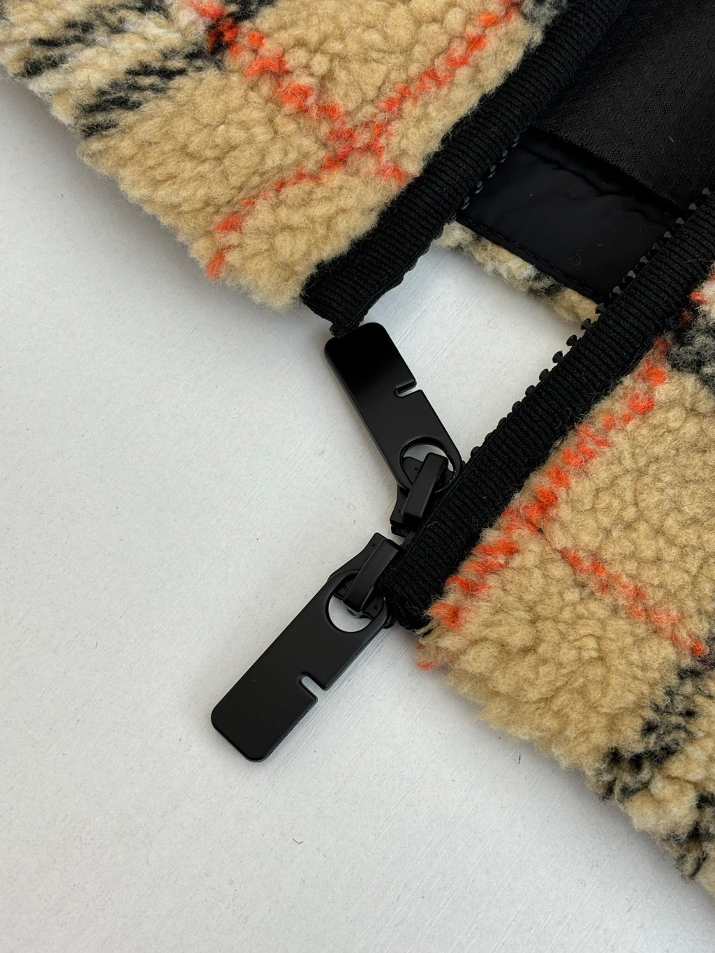 Black zipper tape and cord with plastic pull on plaid jacket cuff