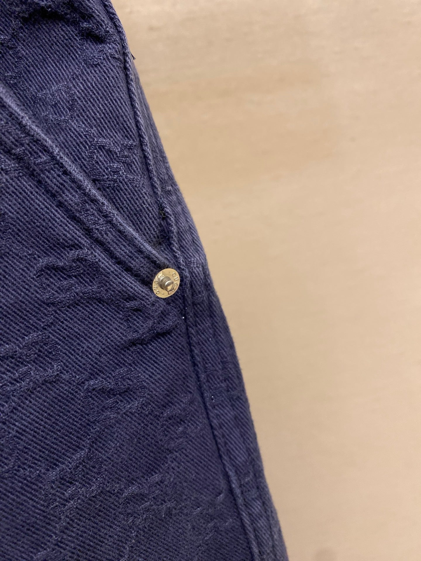 Gucci pants pocket and seam close-up, navy textured fabric with metal button