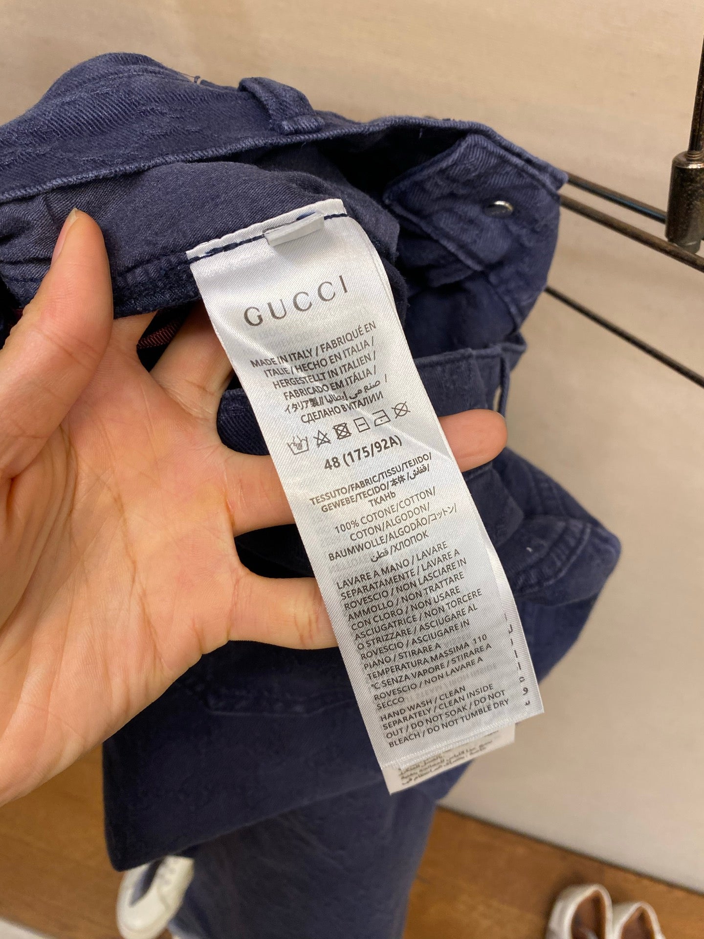 Gucci pants care label close-up, blue fabric with white brand tag