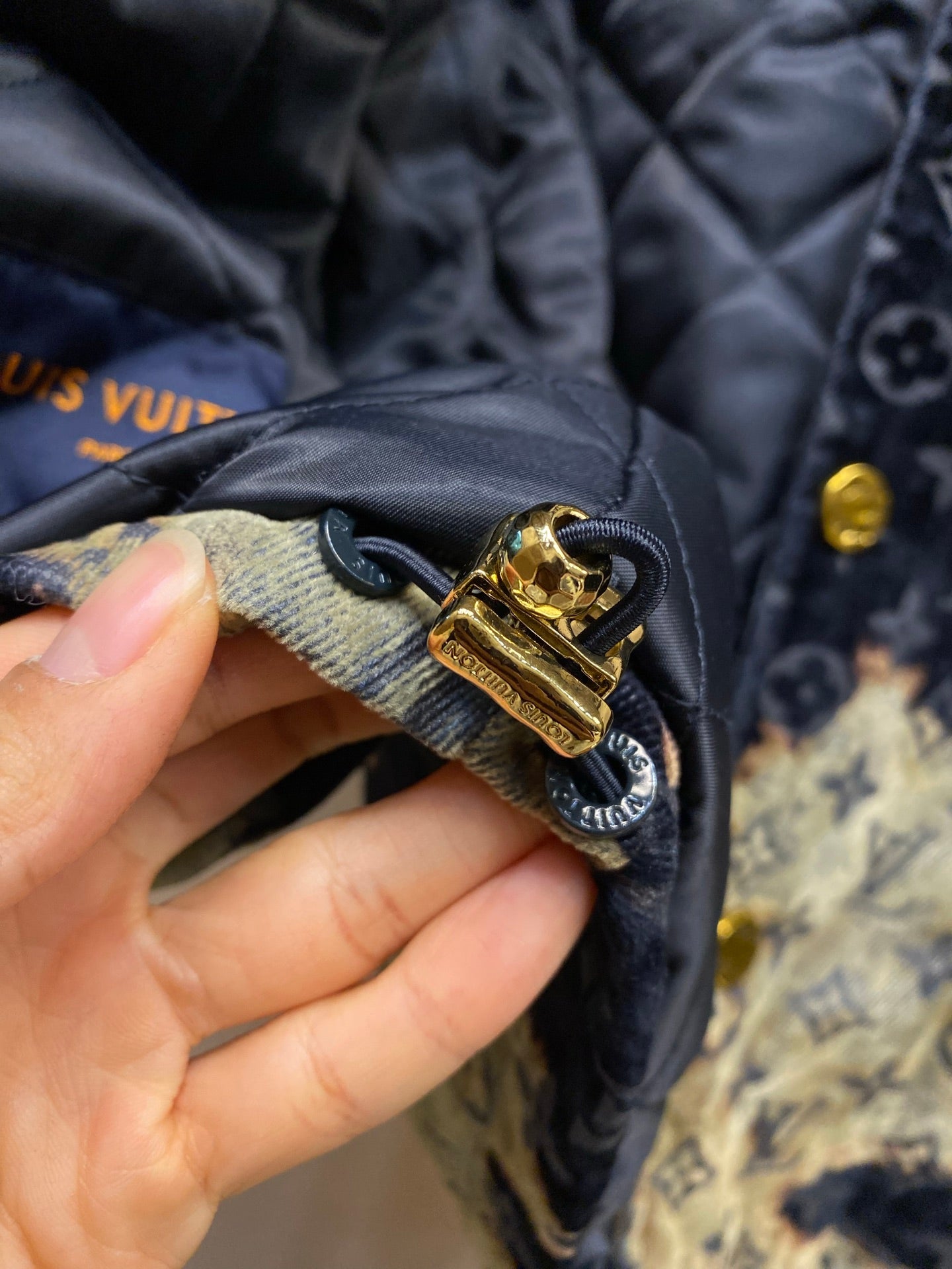 Gold snap and belt-loop detail on navy Louis Vuitton monogram jacket