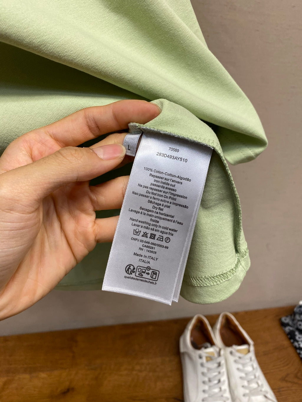 Light green Dior T-shirt with care label tag attached near neckline
