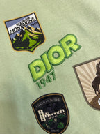Close-up of light green Dior logo T-shirt with “Dior 1947” and crest graphic