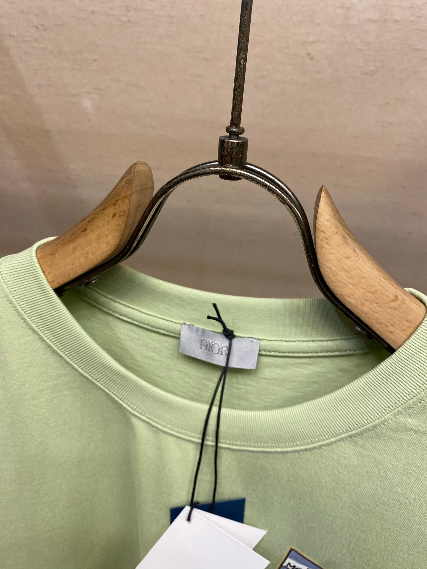 Light green crewneck T-shirt collar with Dior tag on hanger clips