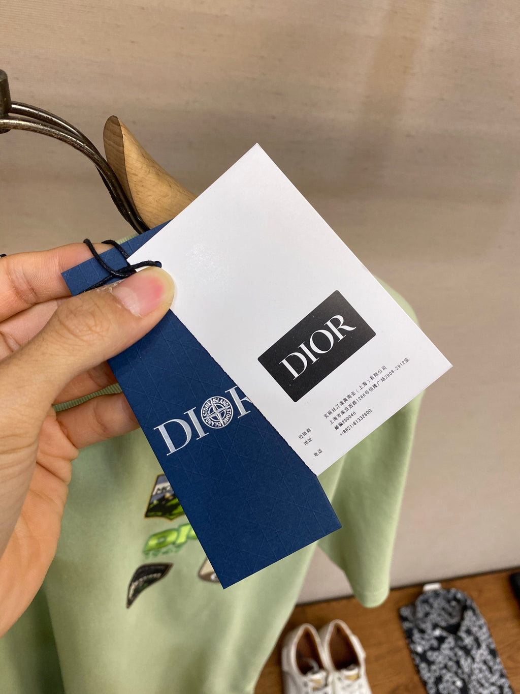 Light green Dior T-shirt with white and blue hanging brand tags in front