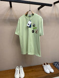 Light green Dior graphic T-shirt with crew neck and multiple logo patches at chest