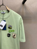 Light green Dior graphic T-shirt sleeve and chest logos with hanging brand tags