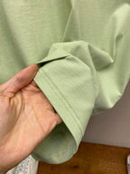 Light green Dior T-shirt fabric sleeve hem shown in hand