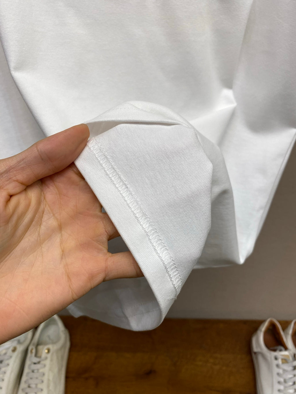 White T-shirt hem and sleeve cuff held in hand, soft cotton fabric