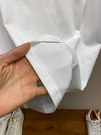 White T-shirt hem and sleeve cuff held in hand, soft cotton fabric