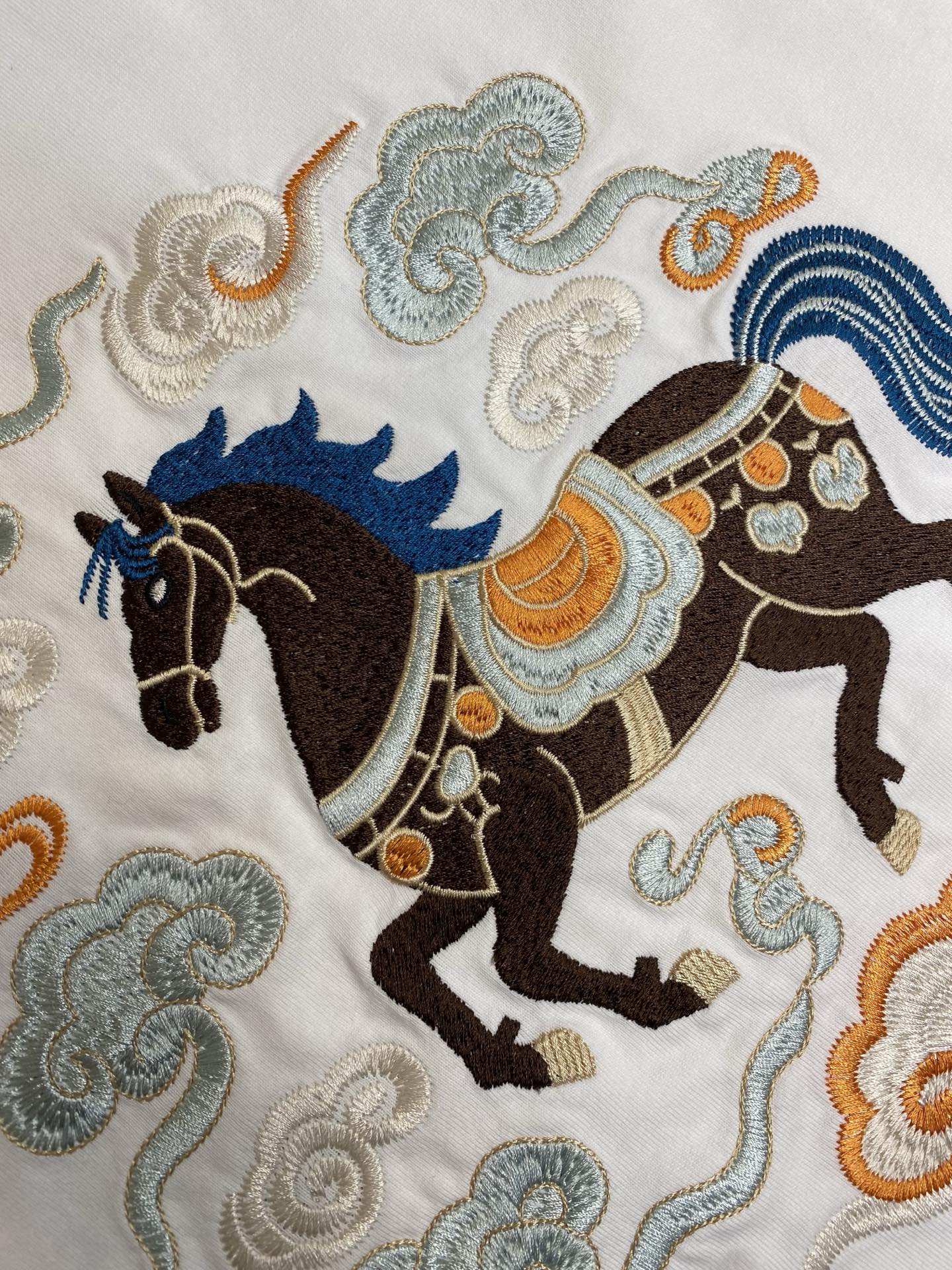 Embroidered horse and cloud motifs on a white T-shirt