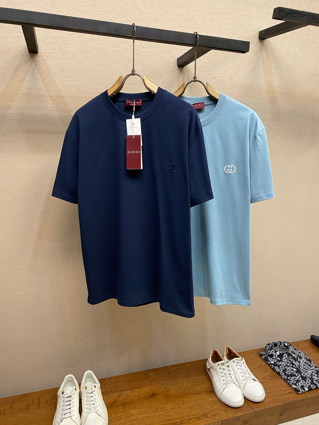 Navy and light blue Gucci crew-neck T-shirts on rack with hanging tags