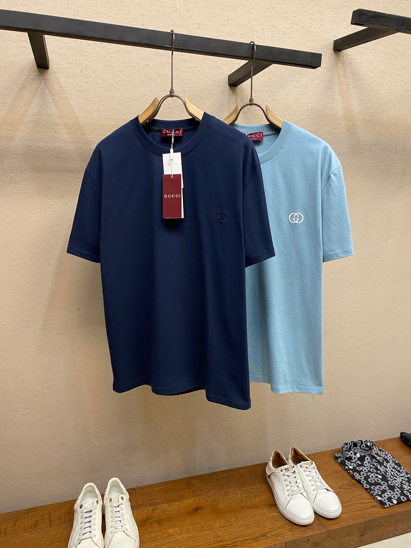 Navy and light blue Gucci crew-neck T-shirts on rack with hanging tags