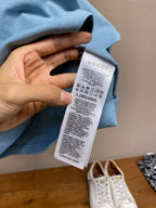 Light blue Gucci T-shirt with care label tag held near neckline