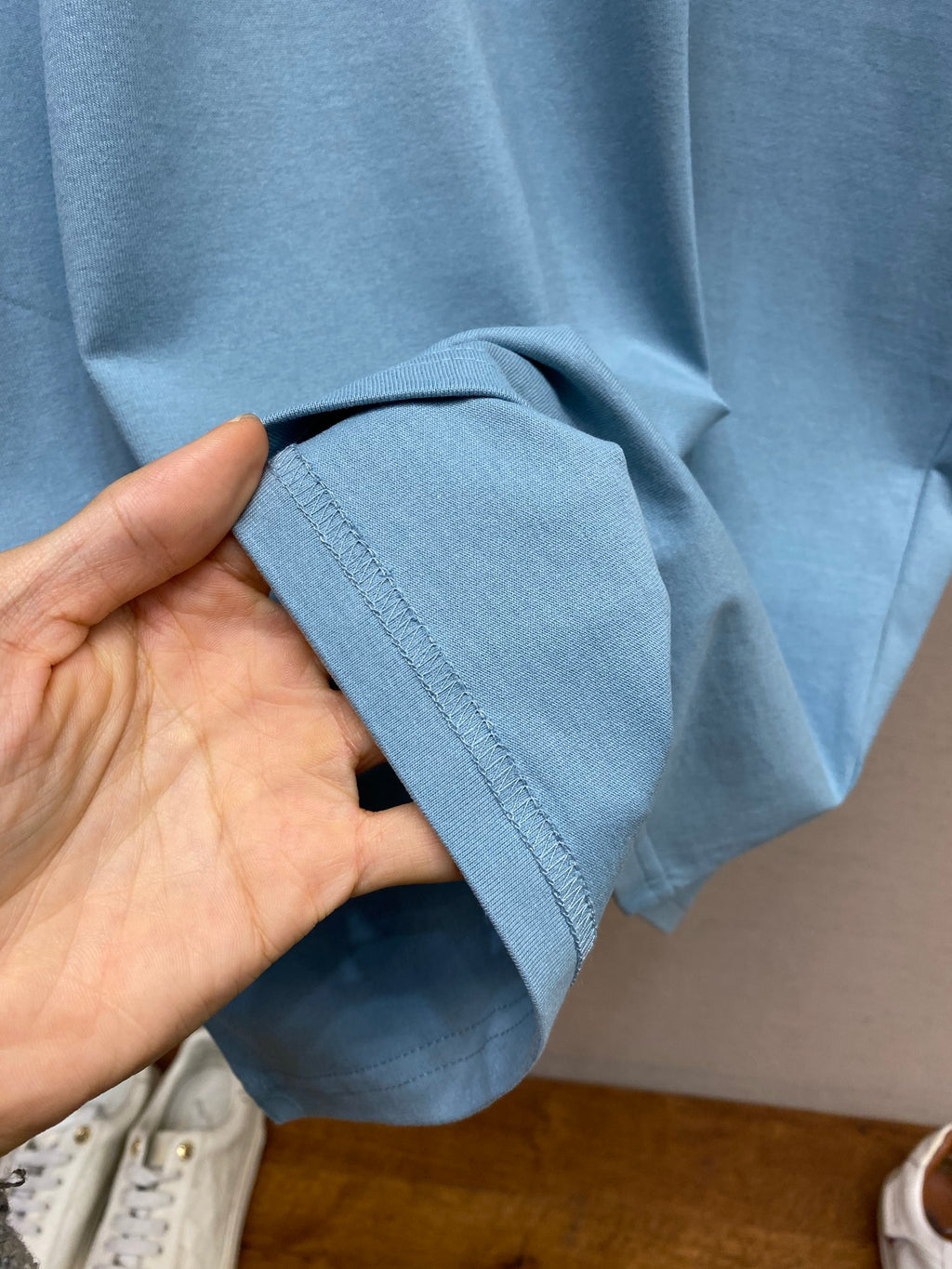 Light blue T-shirt sleeve cuff held in a hand