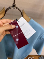 Light blue Gucci T-shirt with maroon and white hanging brand tags