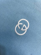 Embroidered white Gucci logo on light blue fabric