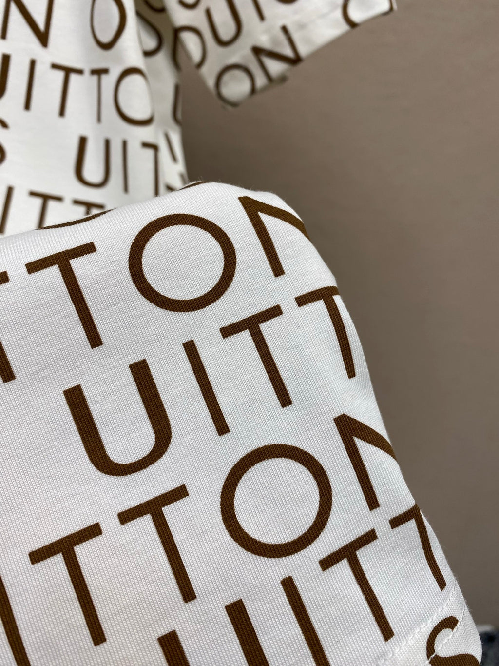 Louis Vuitton monogram T-shirt sleeve detail, white with brown repeating letters