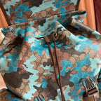 Gucci camo-print backpack with drawstring tie, zipper pulls, and branded front detail