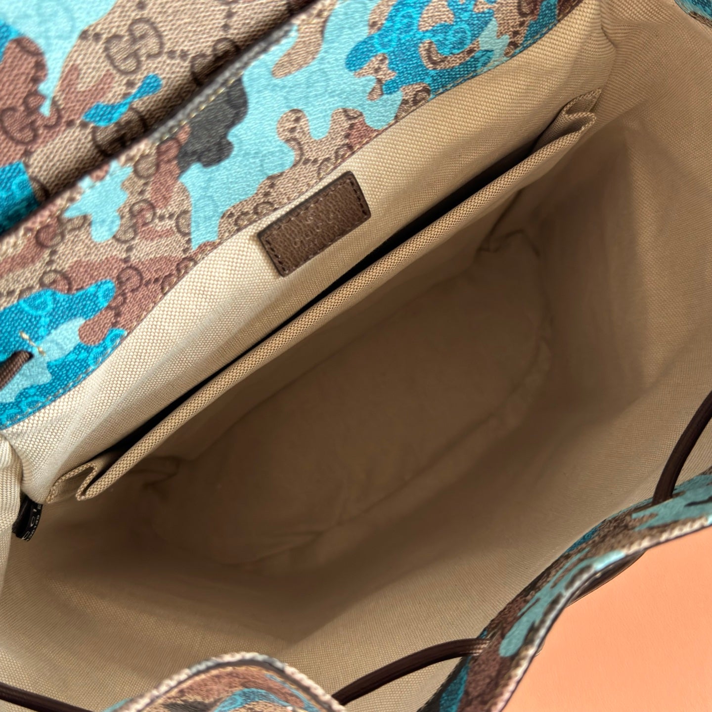 Gucci backpack interior with beige lining and camo-print zip pocket wall panel