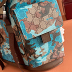 Gucci camo-print backpack front corner with flap, buckle strap, and brown leather bottom