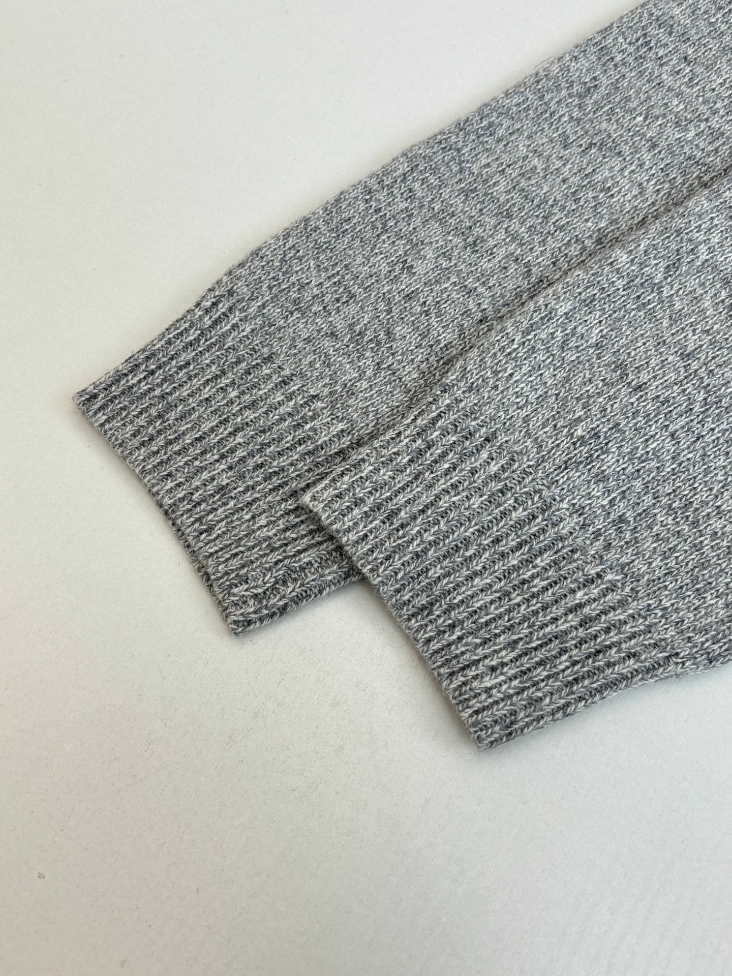 Gray knit sweater sleeve close-up with fine textured knit pattern