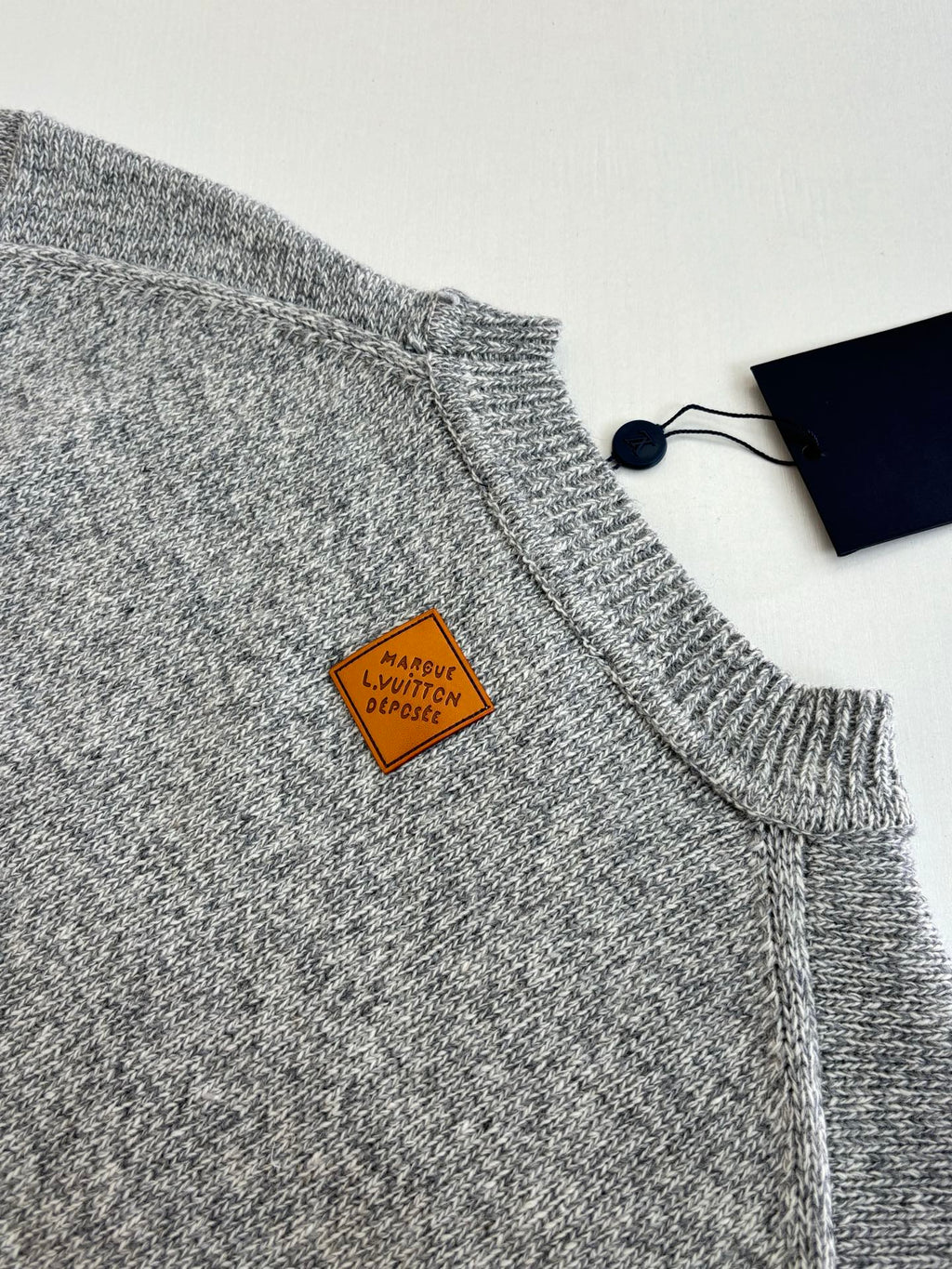 Gray knit sweater shoulder and collar with small leather tag