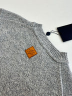 Gray knit sweater shoulder and collar with small leather tag