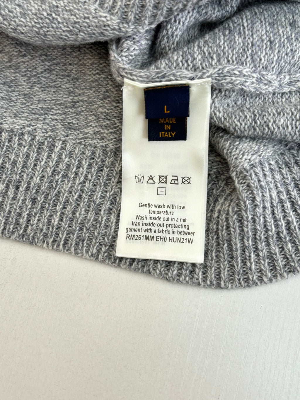 Gray sweater interior care label tag with size and fabric info