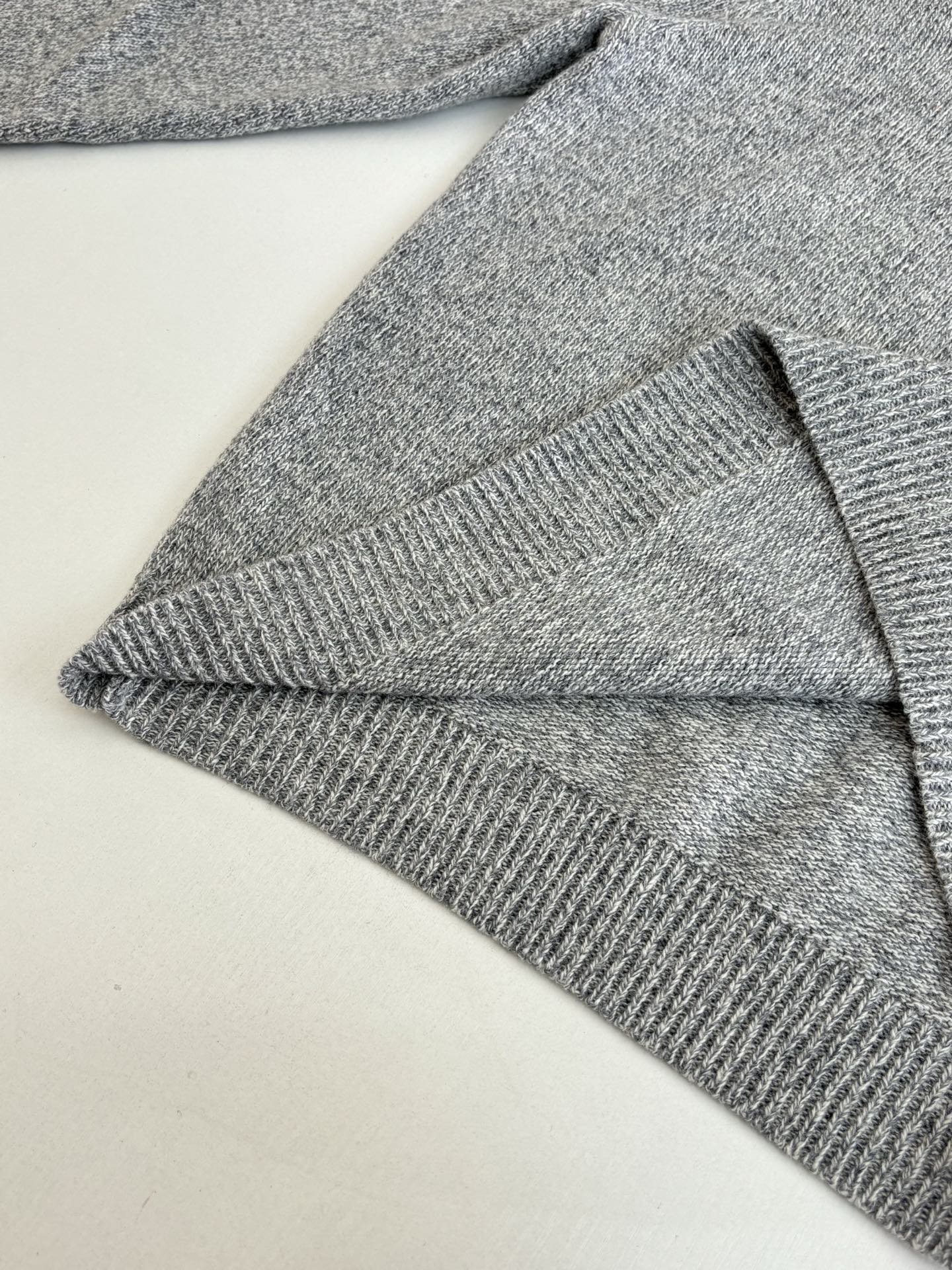 Gray knit sweater sleeve and hem close-up with ribbed knit cuff