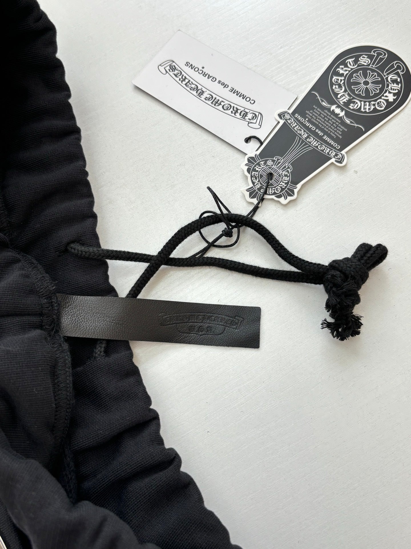 Black shorts with drawstring ties and hang tags attached to waistband