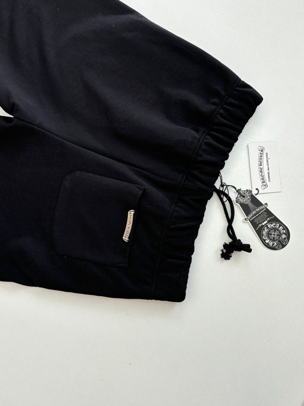 Black shorts with elastic cuffs, drawstring cord, and side zipper pocket