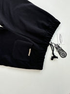 Black shorts with elastic cuffs, drawstring cord, and side zipper pocket