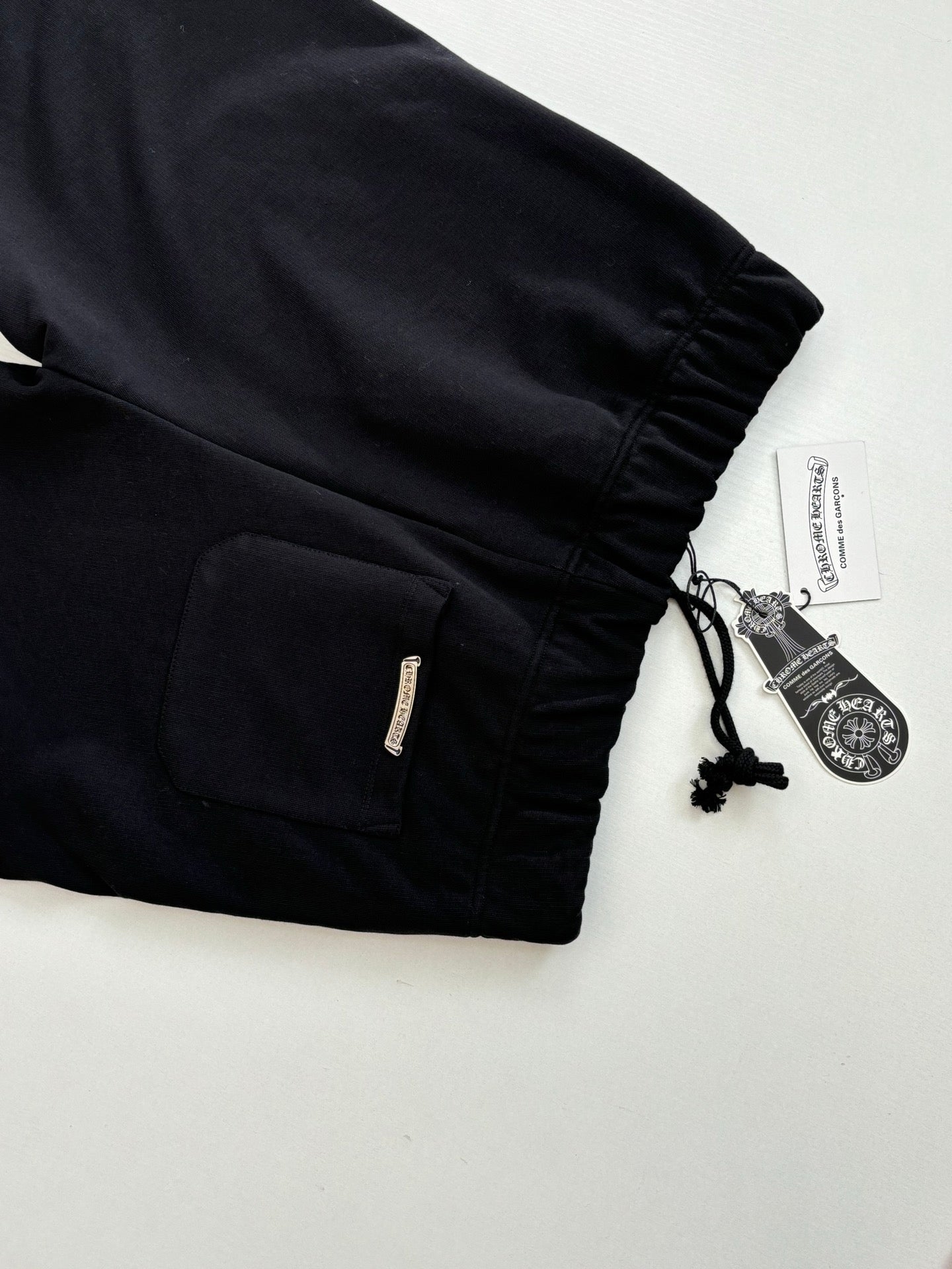 Black shorts with elastic cuffs, drawstring cord, and side zipper pocket