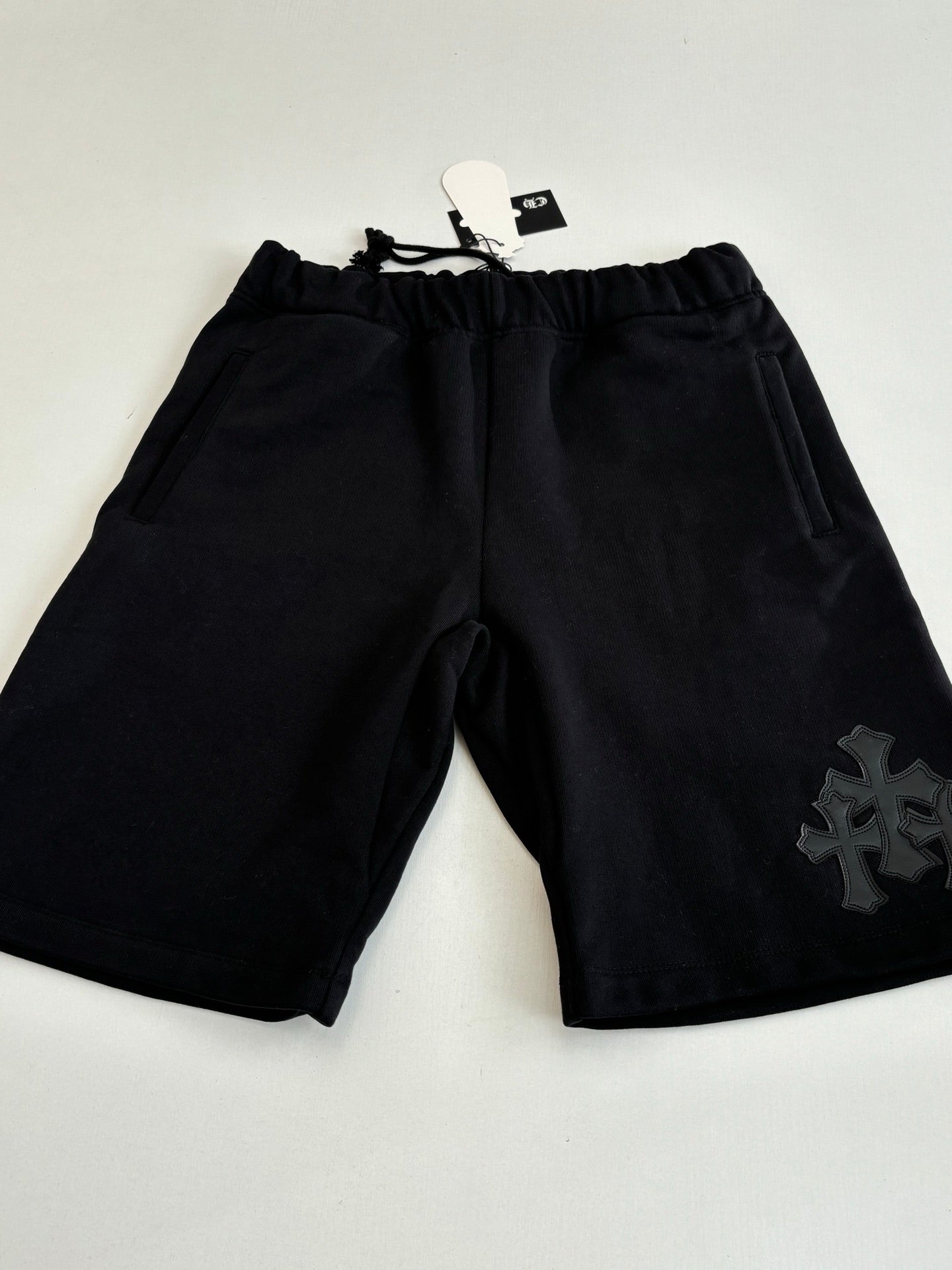 Black drawstring shorts with embroidered side emblem and elastic waistband