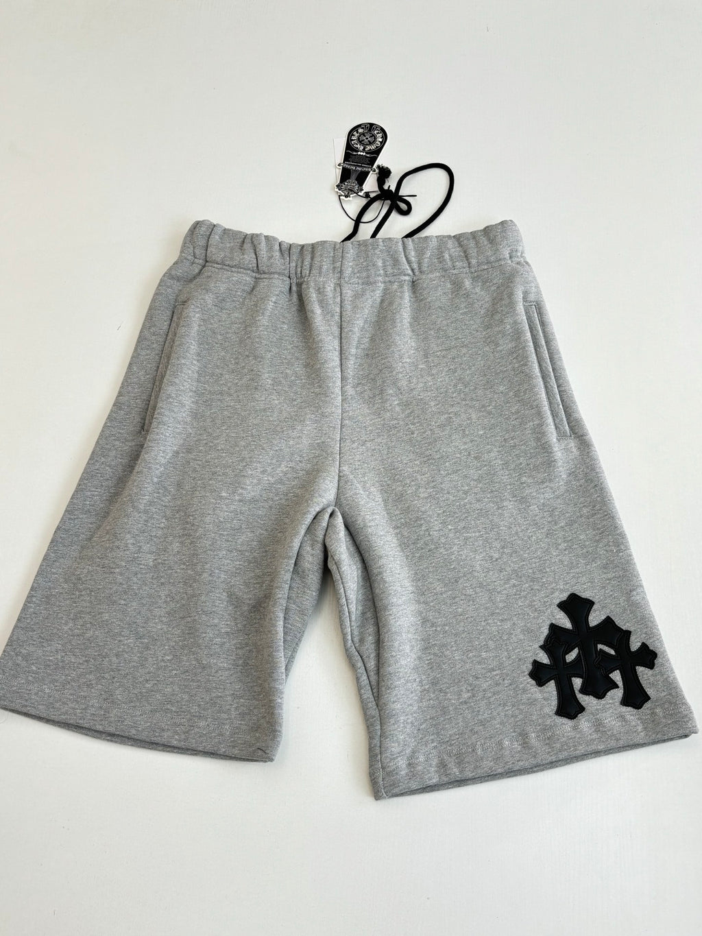 Heather gray shorts with drawstring waistband and black cross-style logo appliqué