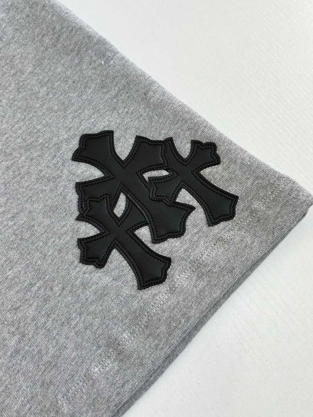 Black cross-style logo appliqué on heather gray shorts