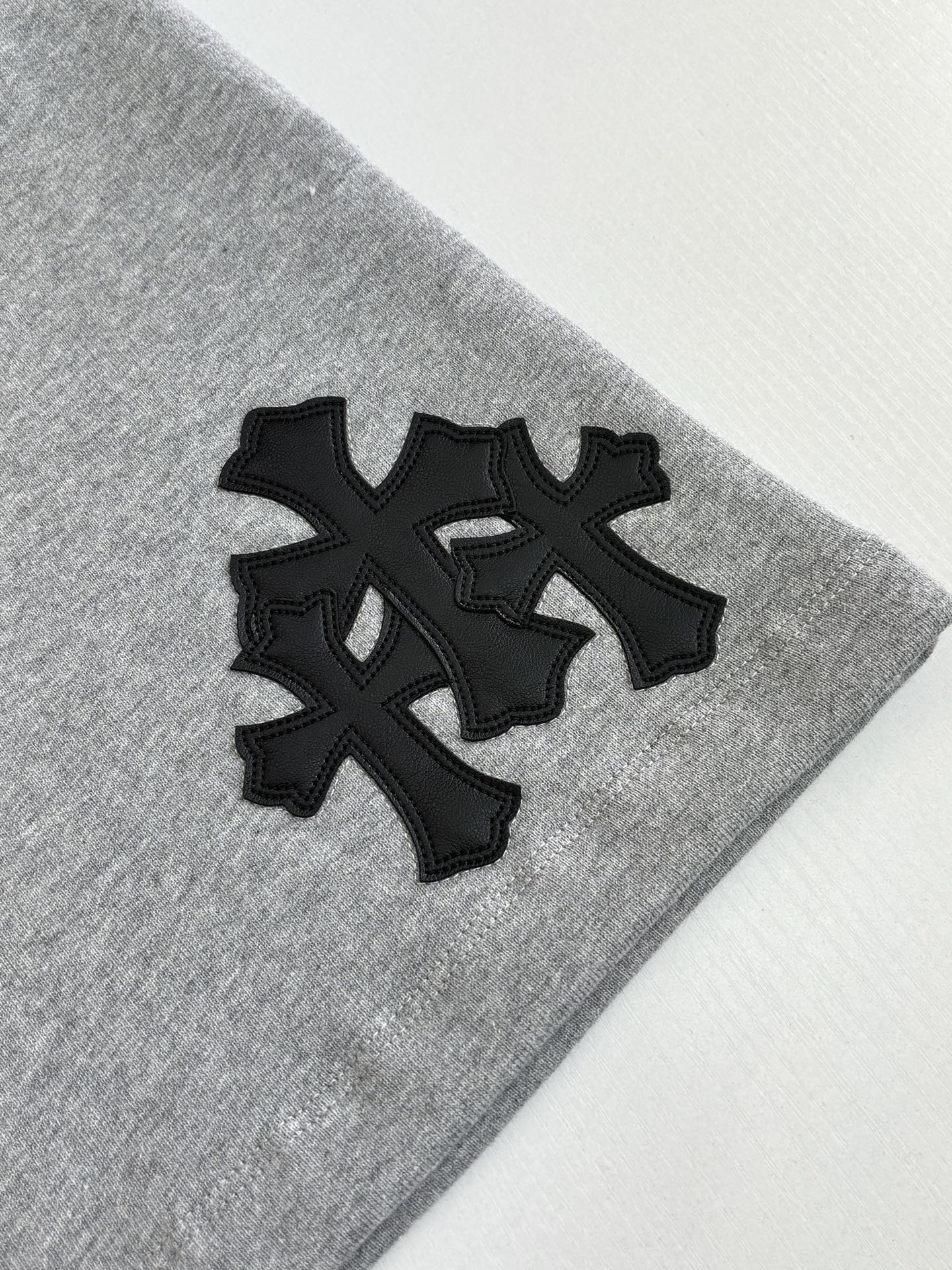 Black cross-style logo appliqué on heather gray shorts