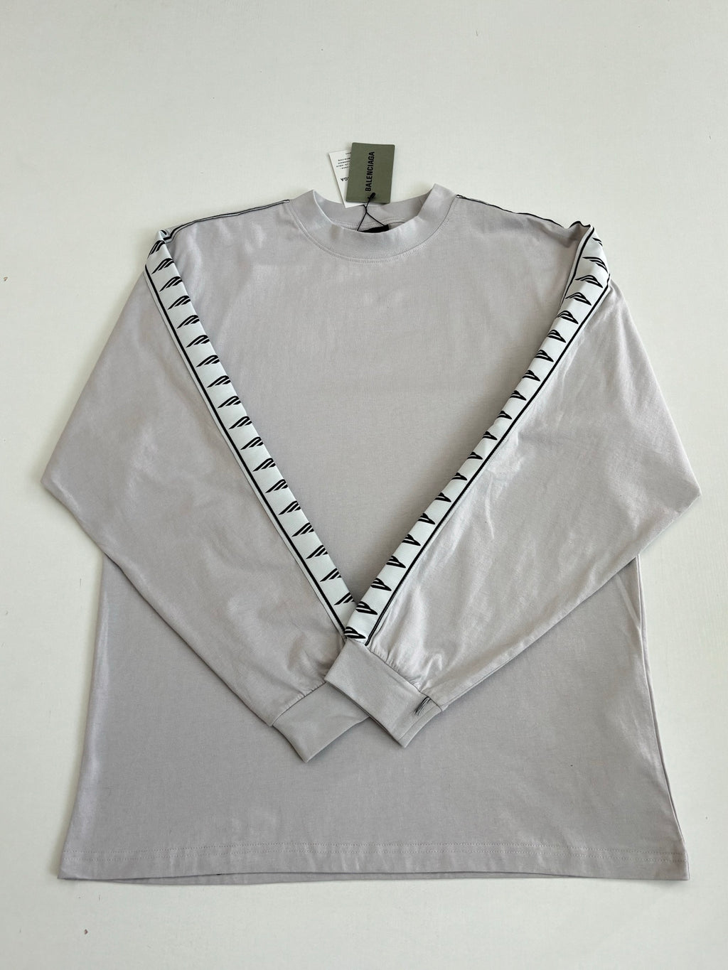 Light gray long-sleeve crewneck top laid flat with black logo V on sleeves