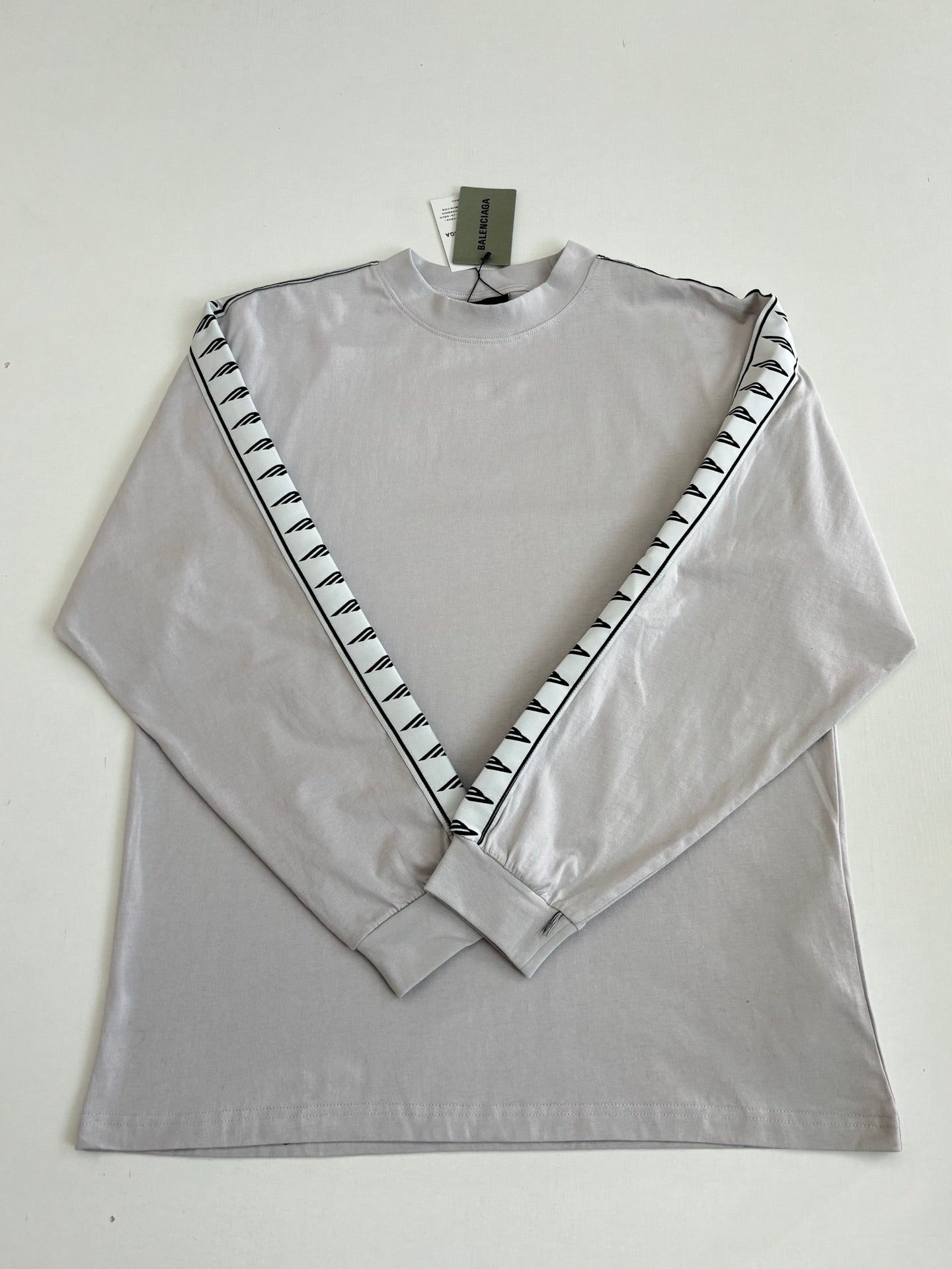 Light gray long-sleeve crewneck top laid flat with black logo V on sleeves