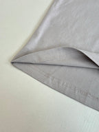 Light gray crewneck top showing stitched side seam and hem detail