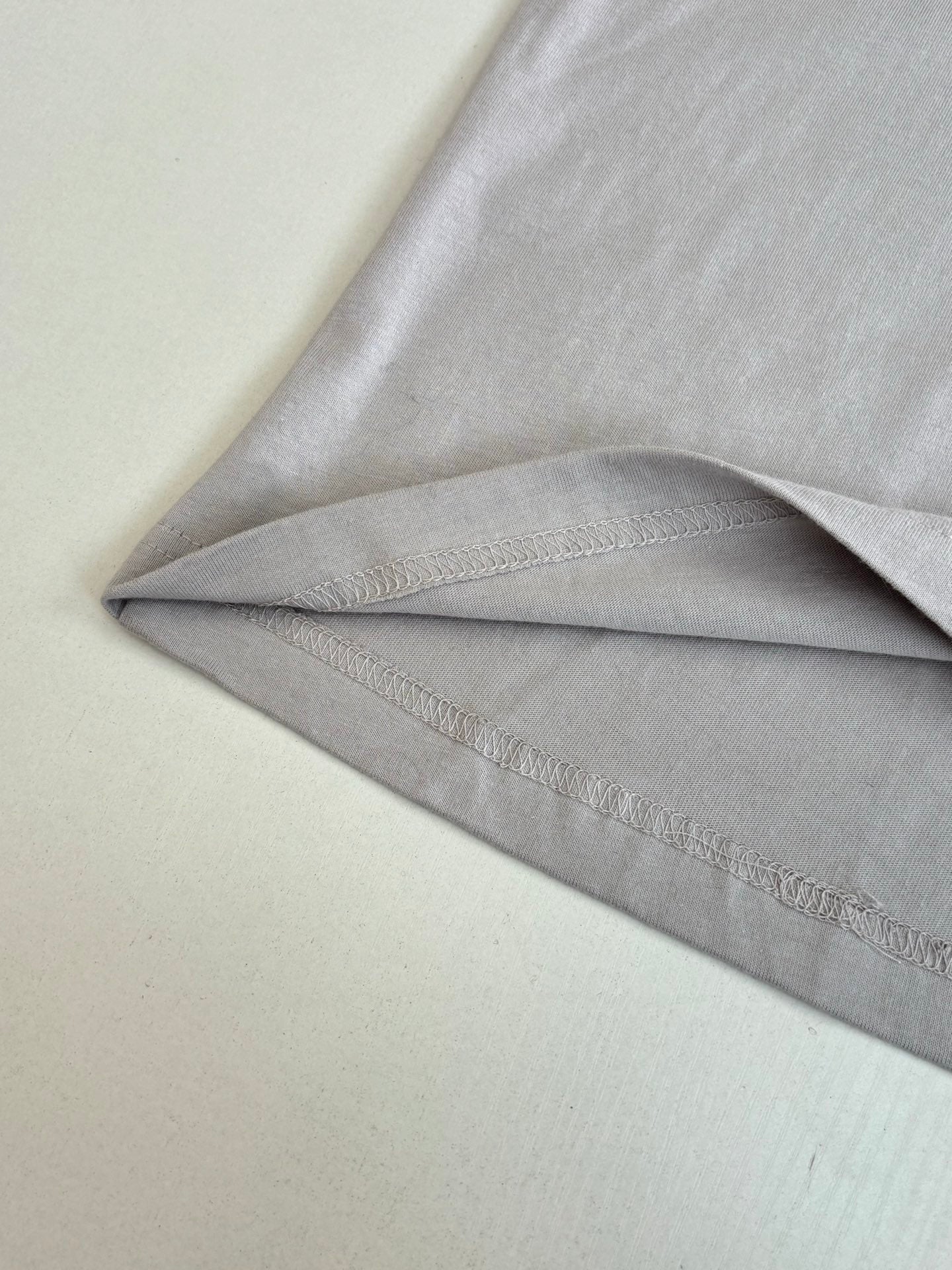Light gray top fabric and stitched hem seam, long-sleeve cuff visible