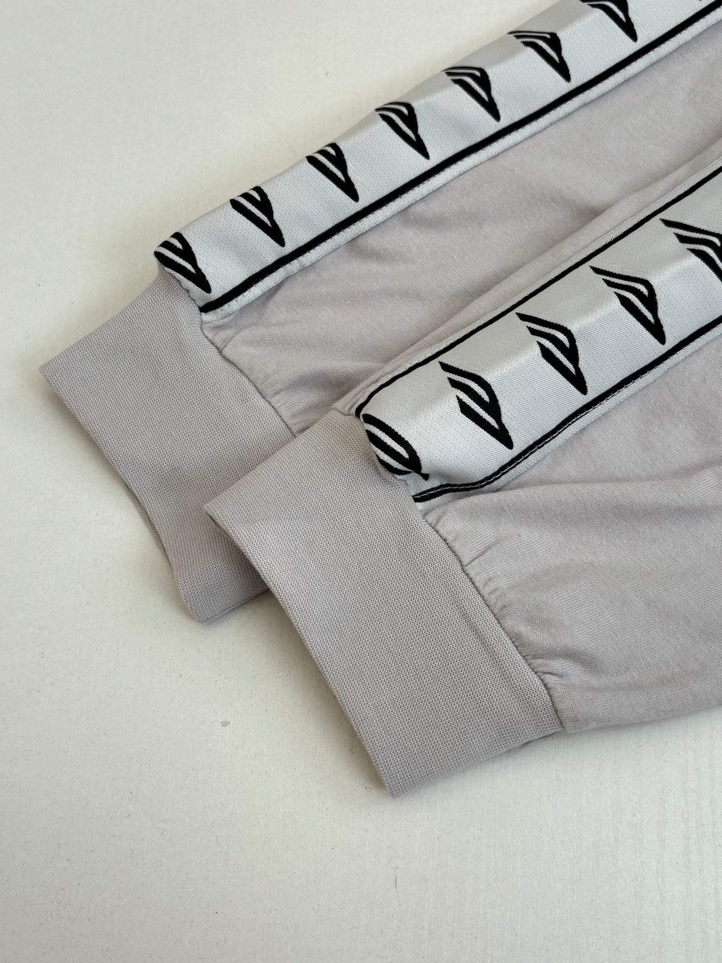 Light gray sleeve cuff with repeating graphic stripe trim and black stitches