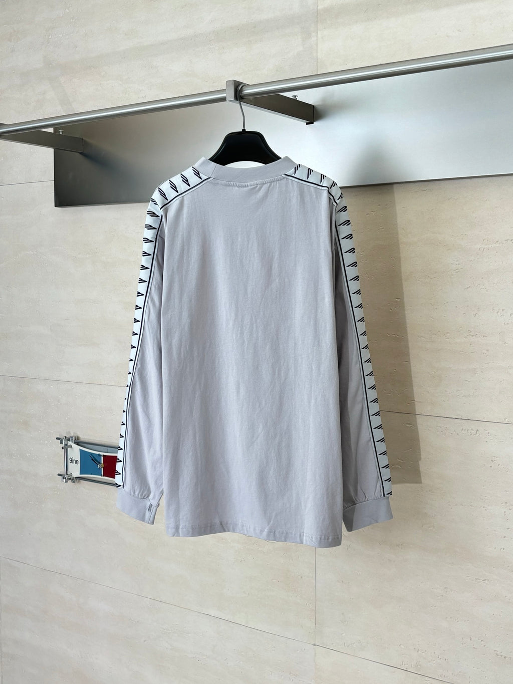 Light gray long-sleeve crewneck top with black logo trim on sleeves, back view