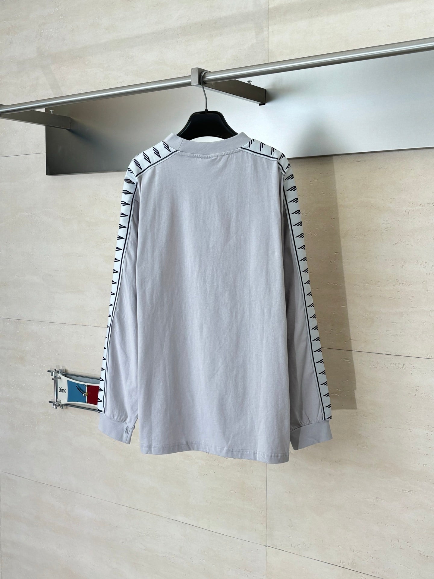 Light gray long-sleeve crewneck top, back view, with graphic stripe sleeve trim