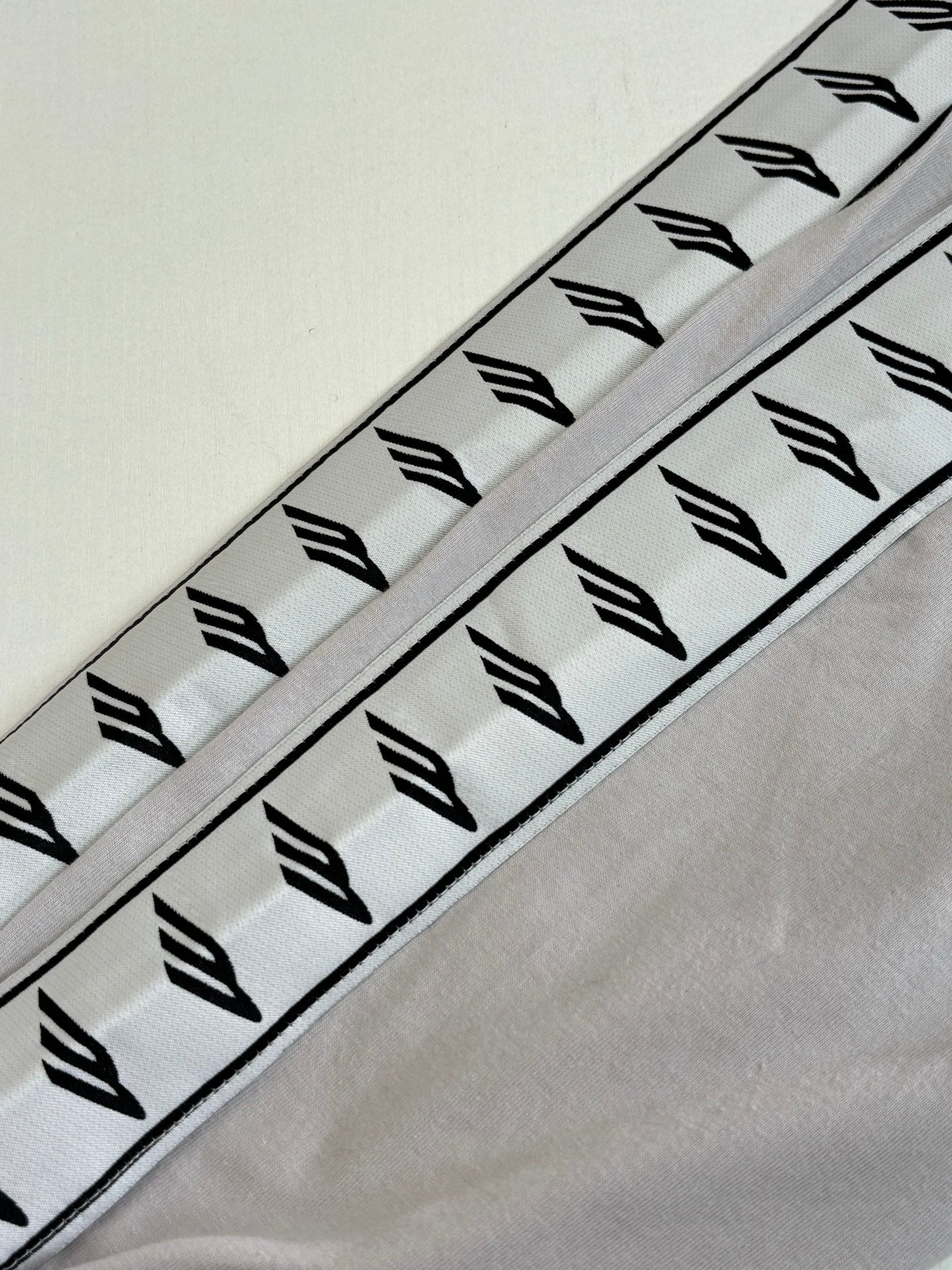 Light gray sleeve with repeating black graphic stripe pattern along seam
